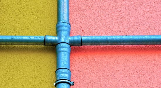 Deux tuyaus bleus se croisant sur un mur coloré